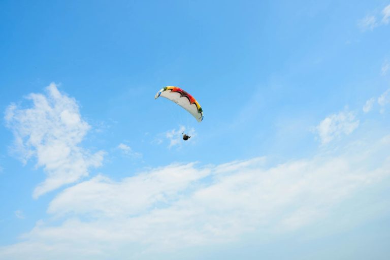 Experience the thrill of paragliding against a bright blue sky above Banting, Malaysia.