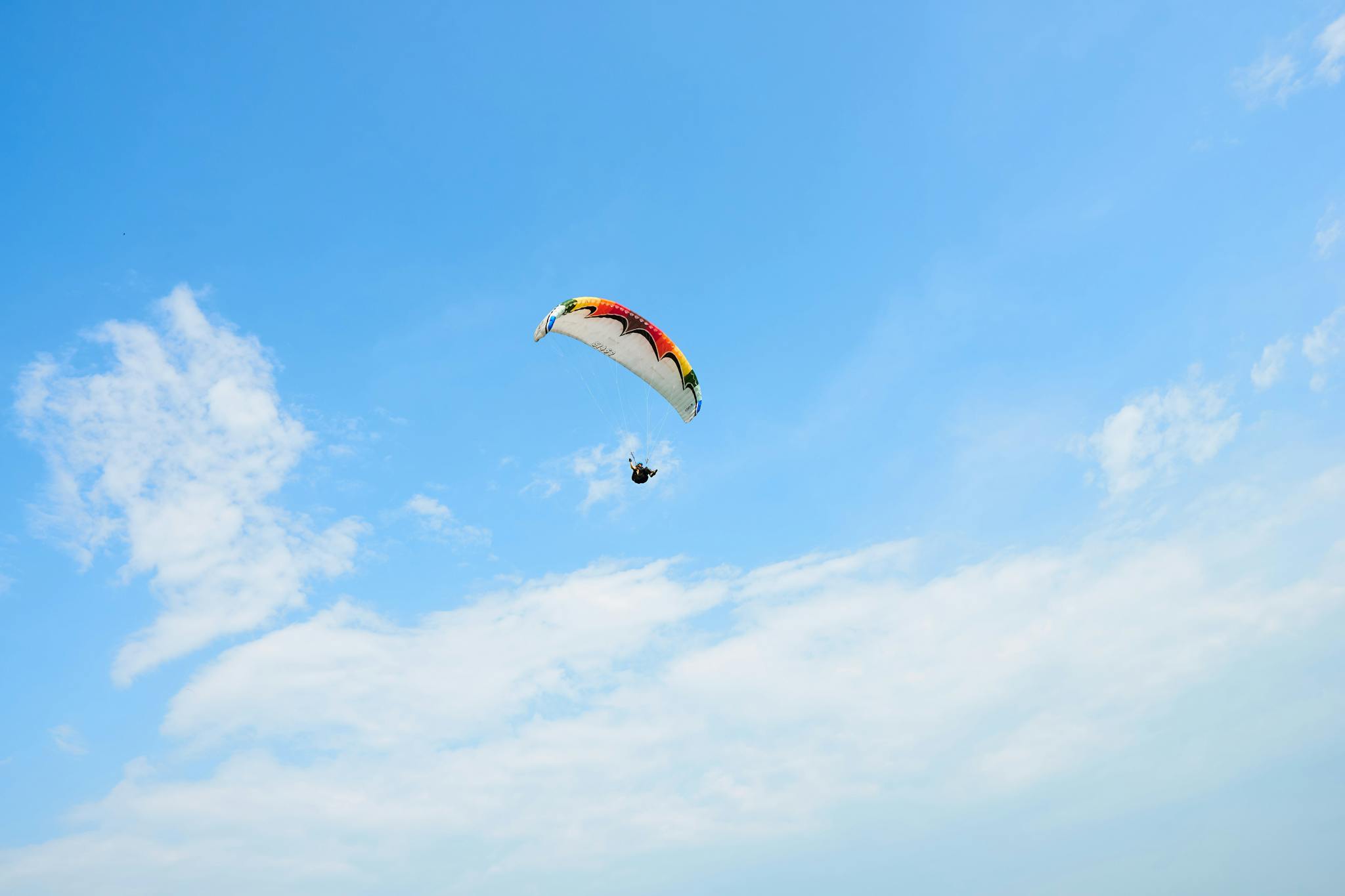 Experience the thrill of paragliding against a bright blue sky above Banting, Malaysia.